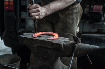 A red-hot metal horseshoe on a blacksmith’s anvil