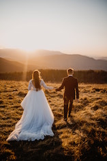 A bride and groom walking across a paddock