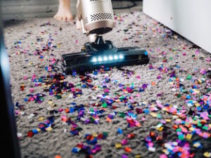 A vacuum cleaner sucking up squares of confetti from a rug