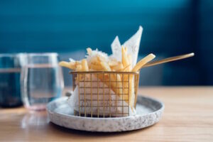 A serve of hot chips in a wire basket on a plate